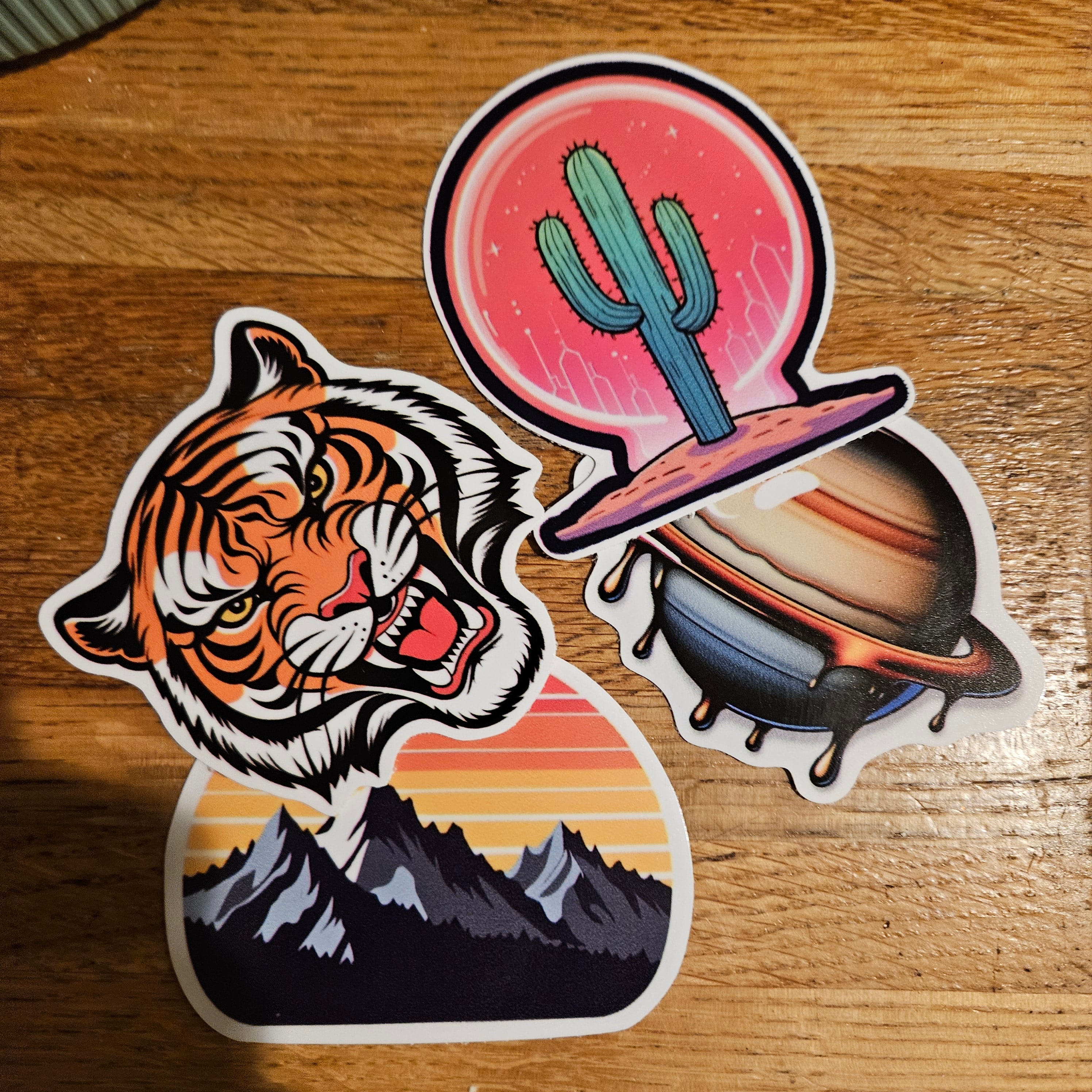 Printed STICKERLY stickers of a tiger, a mountain sunset, and a cactus planet